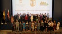 Zdjęcie przedstawia dużą grupę ludzi, kobiety i mężczyźni stojących w dwóch rzędach na sali konferencyjnej na tle wyświetlanej prezentacji z hasłem „Prekonsultacje dotyczące rynku pracy”.