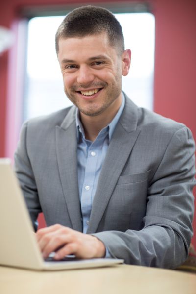 Grafika przedstawia mężczyznę piszącego na laptopie